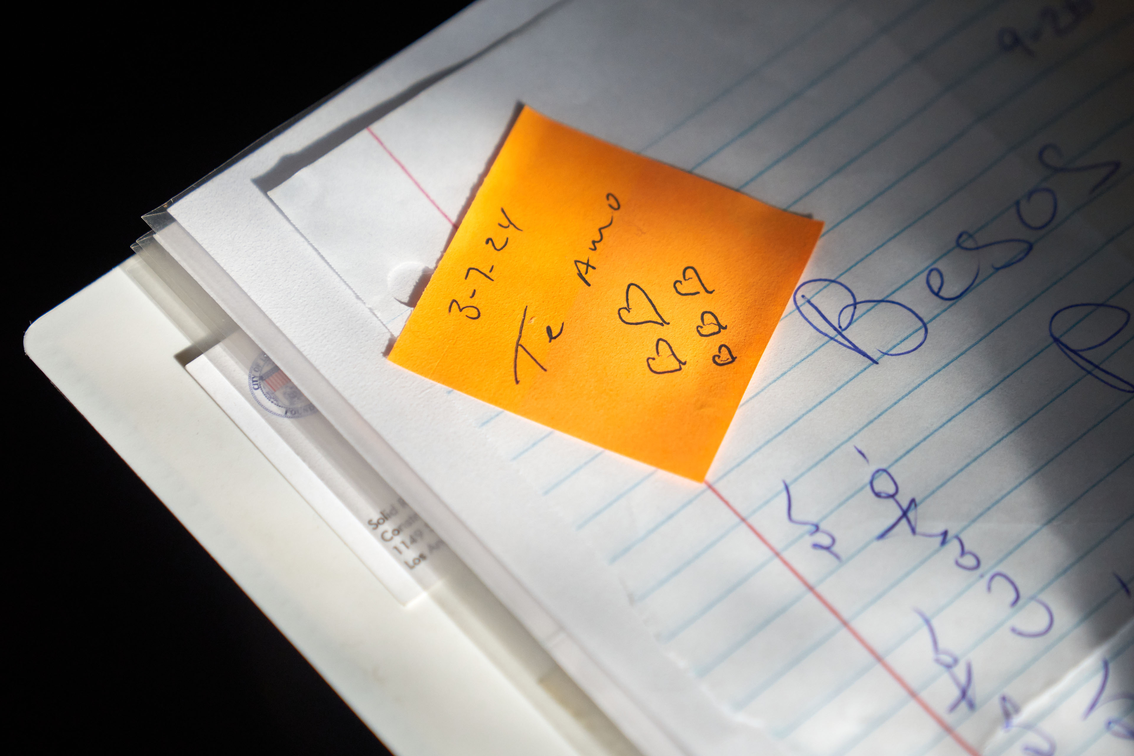 An up-close photograph of a sticky note in a notebook that says, "3-7-24 / Te Amo" with hand-drawn hearts underneath the text.