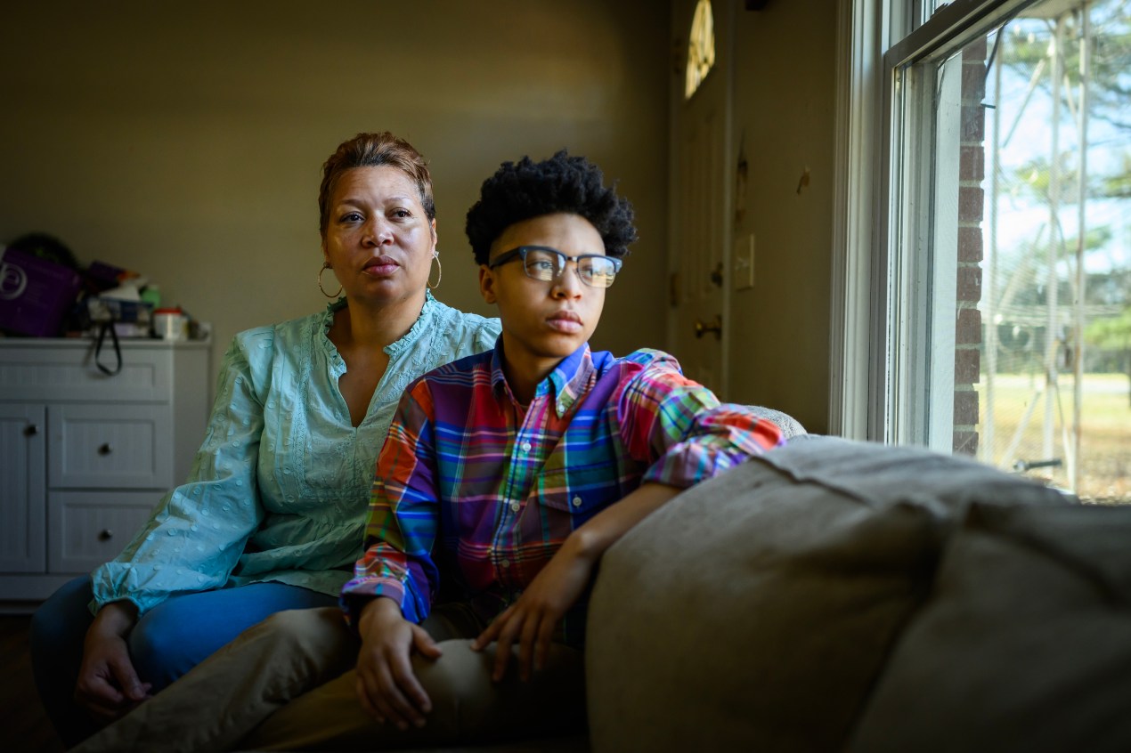 DiJuana Davis and her child Treasure Woodard sit on a couch in their home.