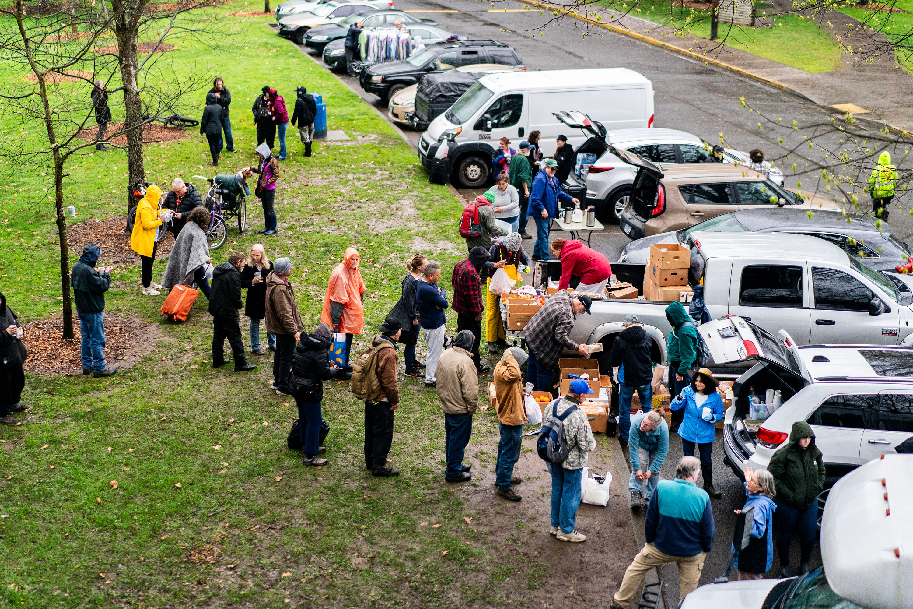 A photo of people lining up to receive supplies out of advocates' trunks at a park in Oregon.