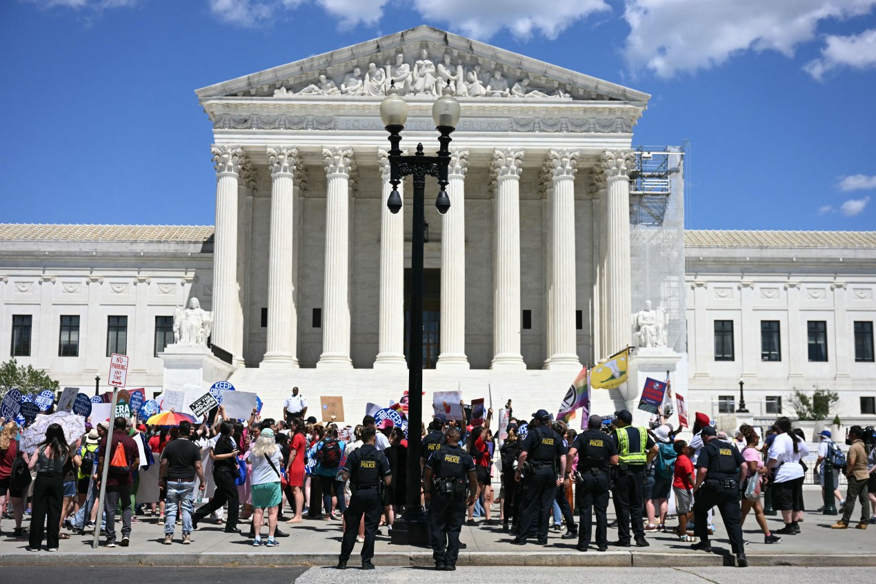 Protesters gather in front of the US Supreme Court building in Washington, DC, on a sunny day.