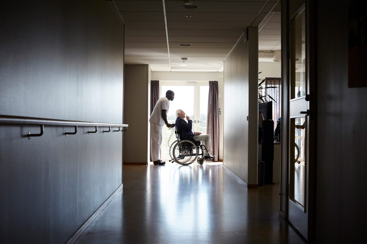 A photo of a nurse pushing an elderly patient in a wheelchair.