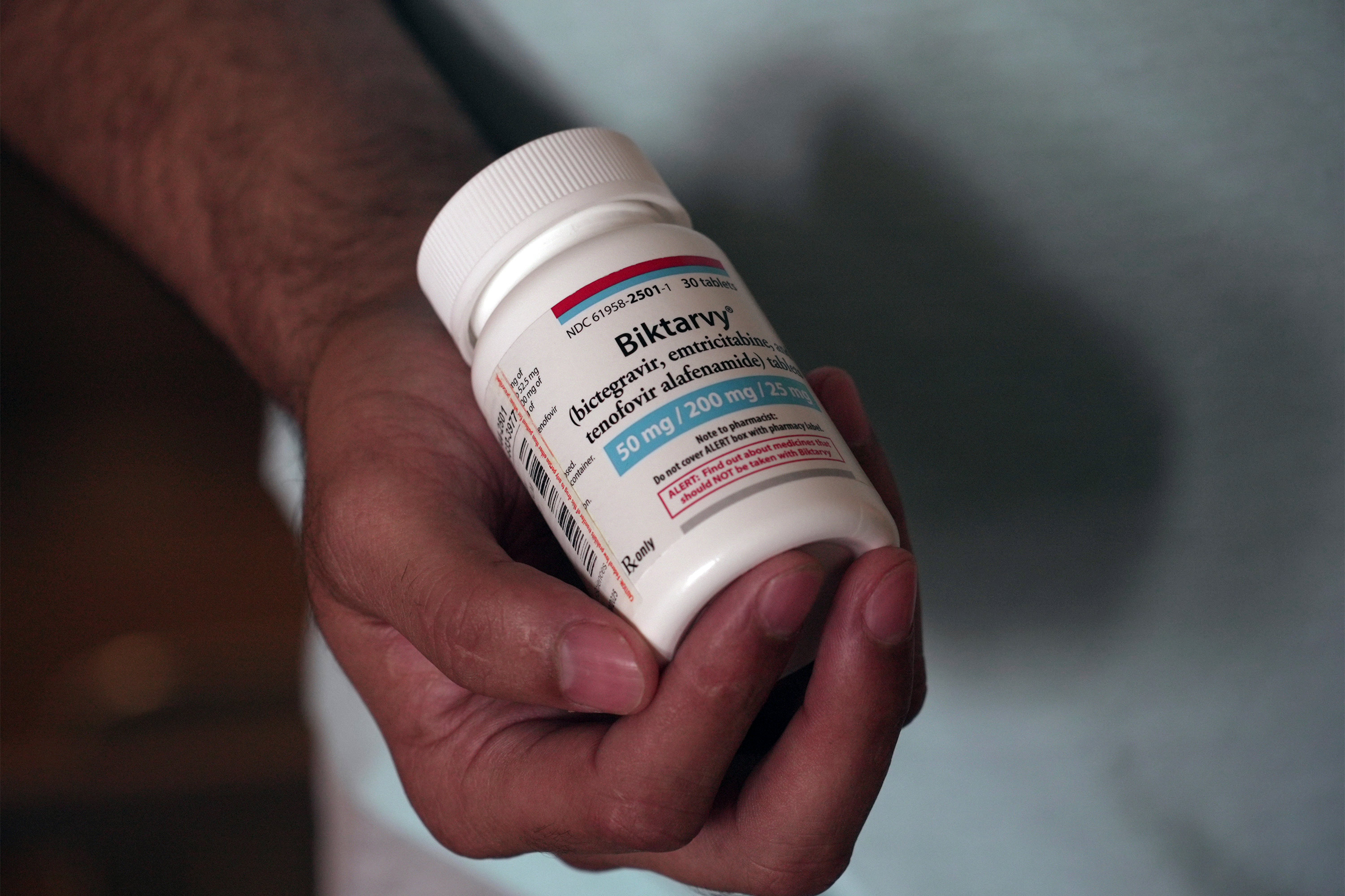 A photo of a hand holding a pill bottle.