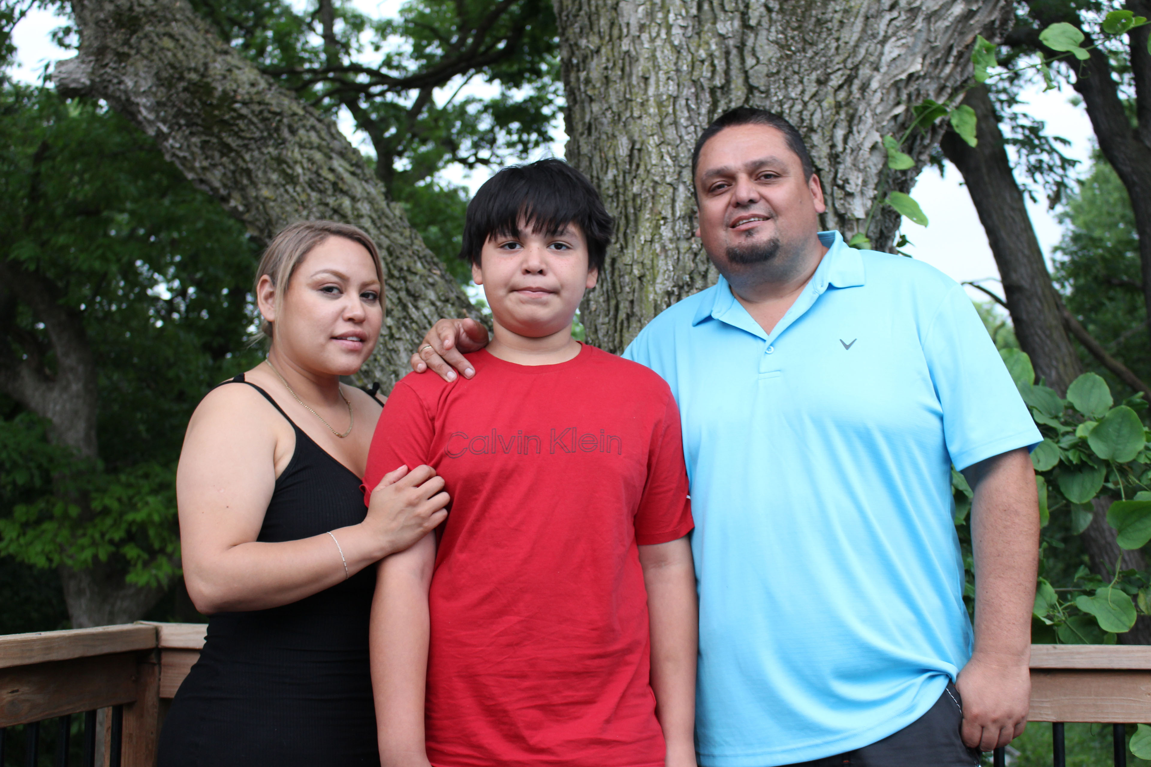 Samuel Arellano, a young boy, (center) stands with his parents, Abigail (left) and Antonio (right), outside their home in Kansas City, Kansas.