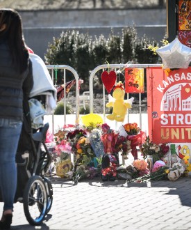 An outdoor memorial is sat up near Union Station in Kansas City. There is a sign that reads, "Kansas City / Strong / United." Flowers, stuffed animals, and other memorial gifts surround the sign.