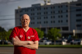 A photo of a nurse standing outside for a portrait in red scrubs.