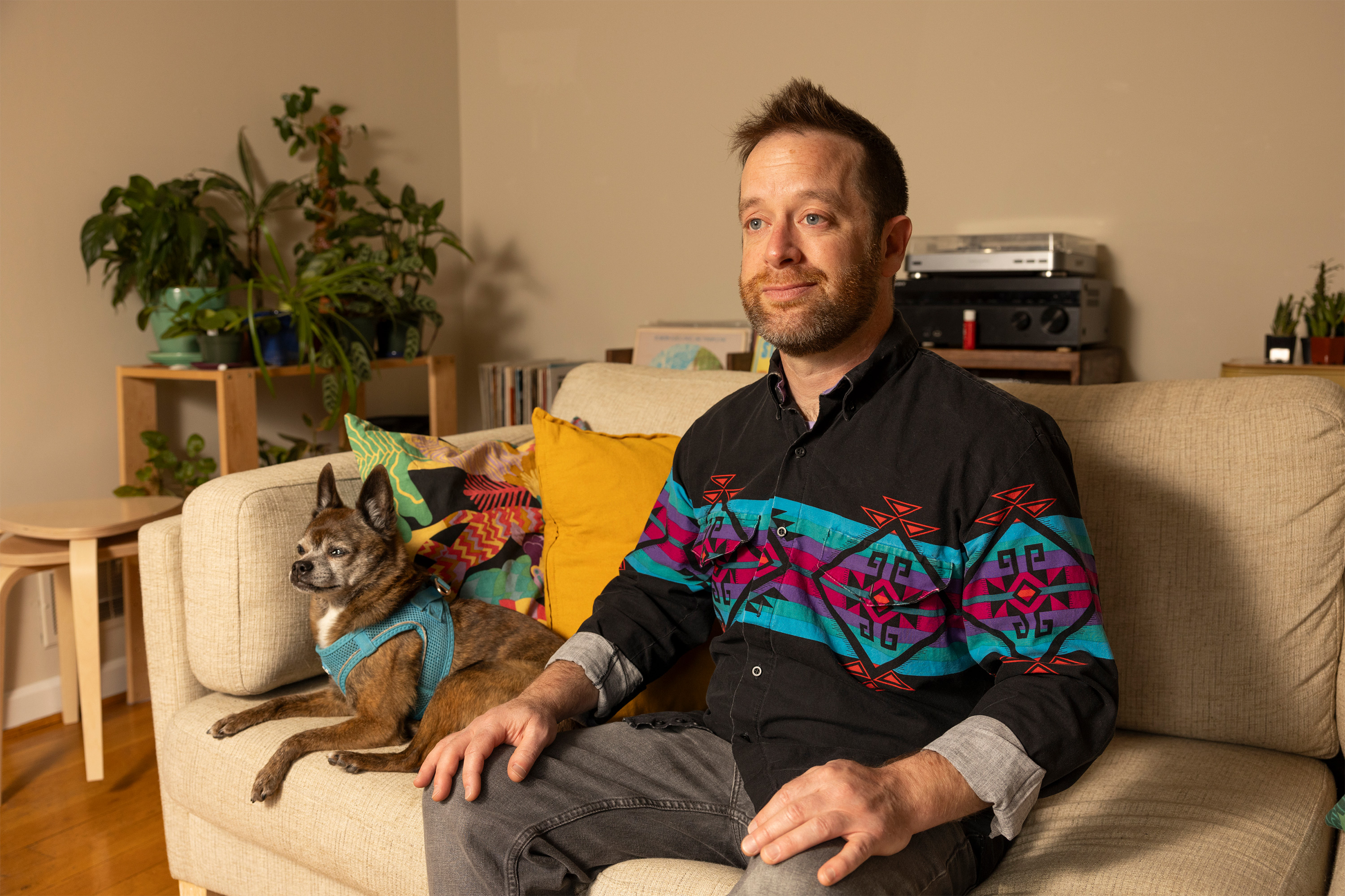 A photo of David Engler sitting on a sofa next to a dog.