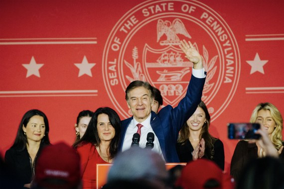 A photo of Mehmet Oz standing at a podium, waving to a crowd.