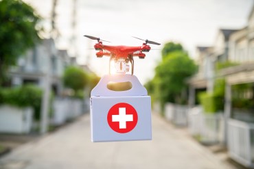 A photo illustration of a drone carrying a emergency medical kit.