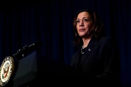 A photo of Kamala Harris on a stage in front of a podium with a microphone.