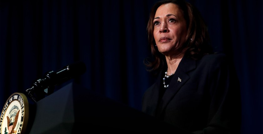 A photo of Kamala Harris on a stage in front of a podium with a microphone.