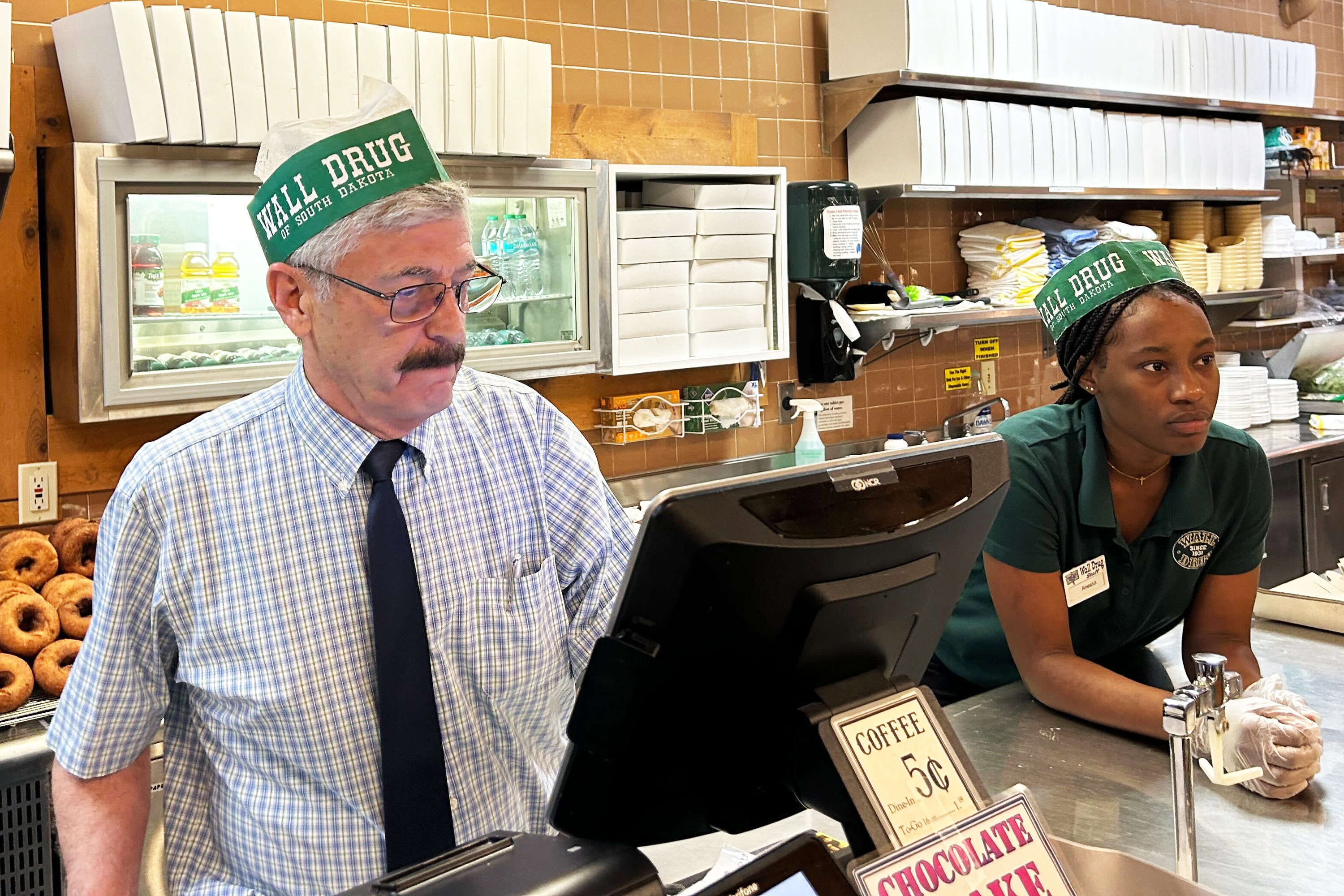 A photo of an older man working behind a counter with a young woman.