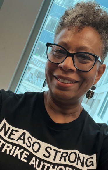 A woman wearing glasses and a t shirt that reads NEA SO STRONG