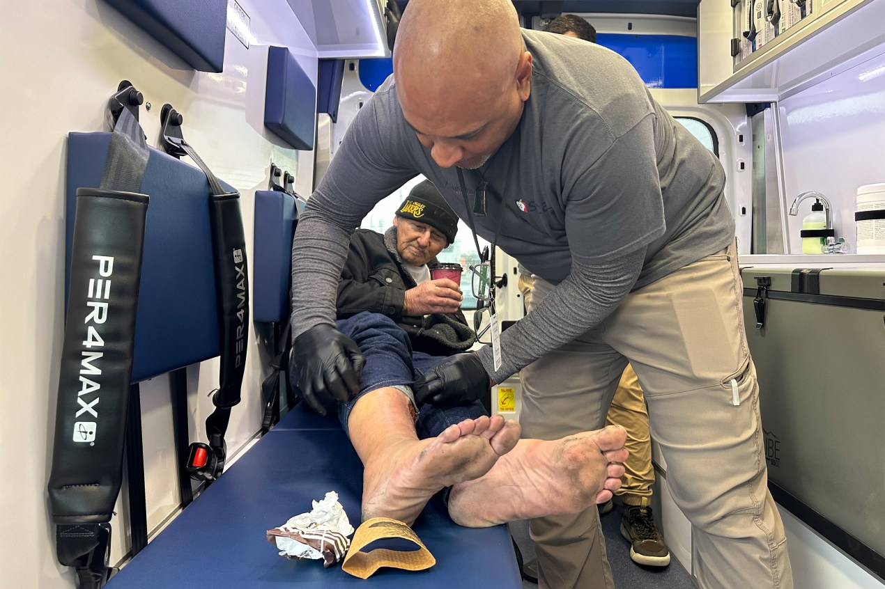 A photo of medical professional treating a wound on a homeless patient.