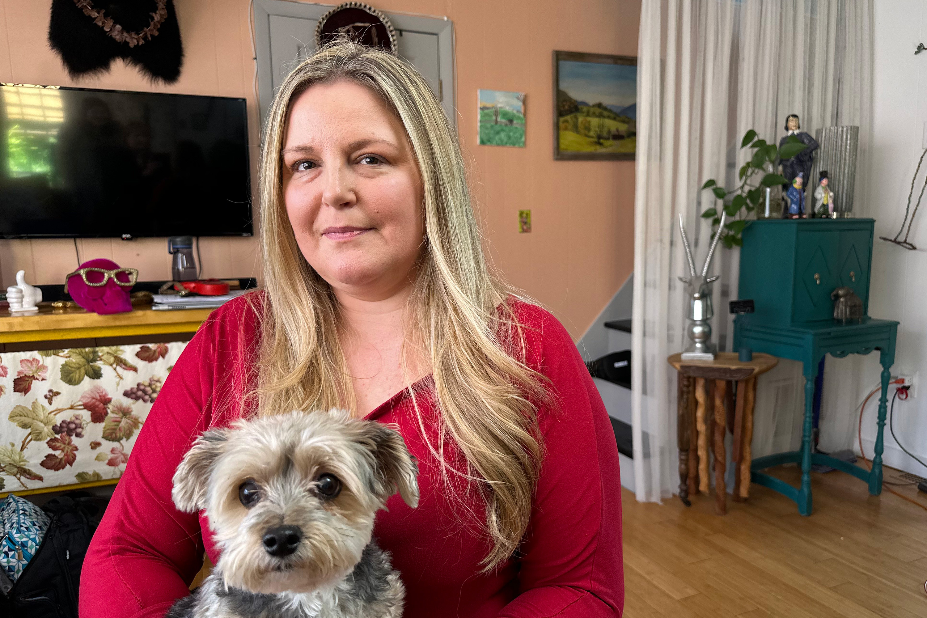 A photo a woman sitting indoors with her dog in her lap.