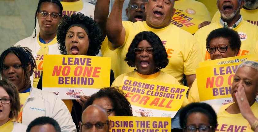 A photo of a group of activists holding signs that read, "Leave no one behind," and "Closing the coverage gap means closing it for all."