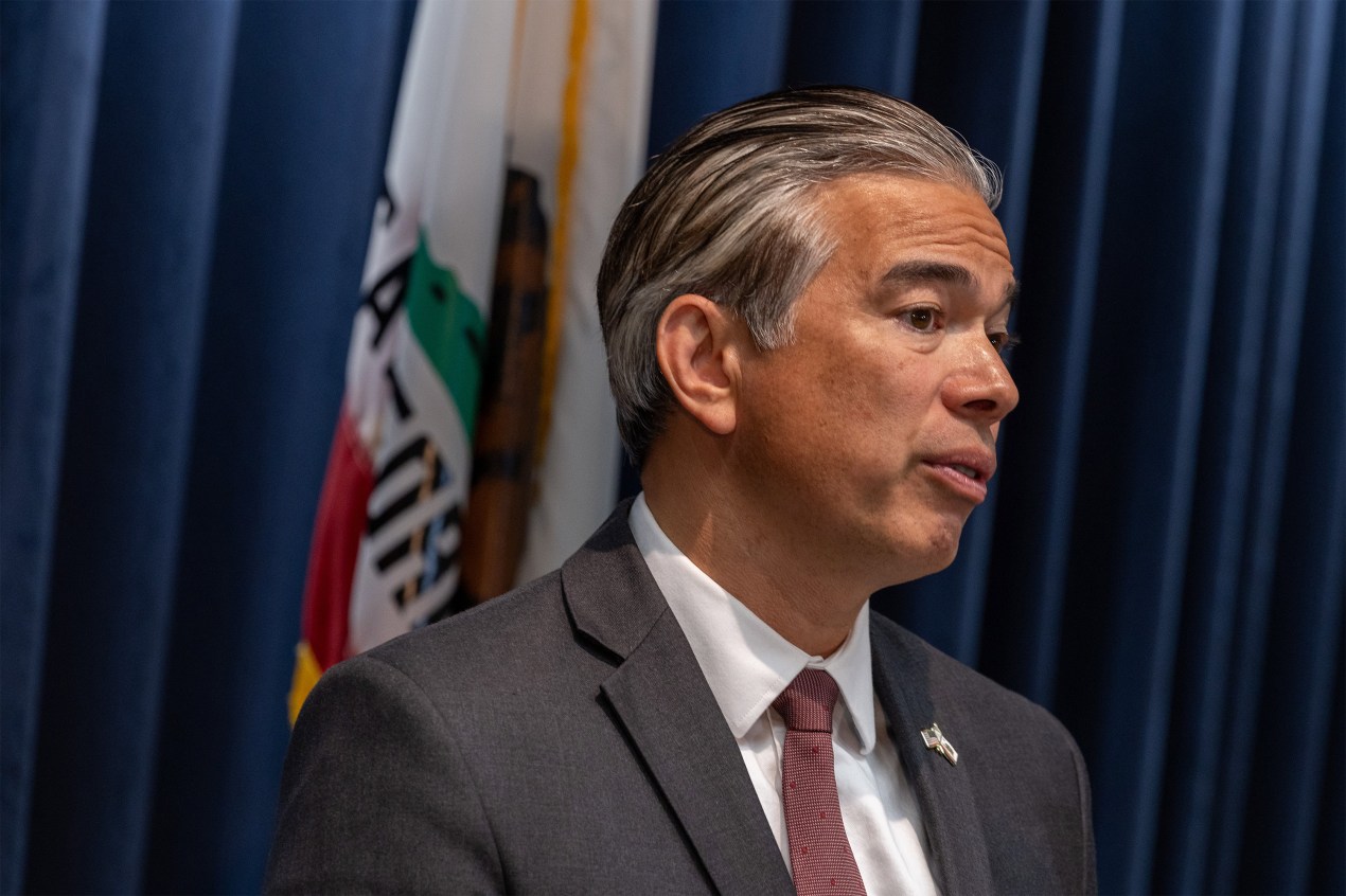 A photo of Rob Bonta speaking in front of a Californian flag.