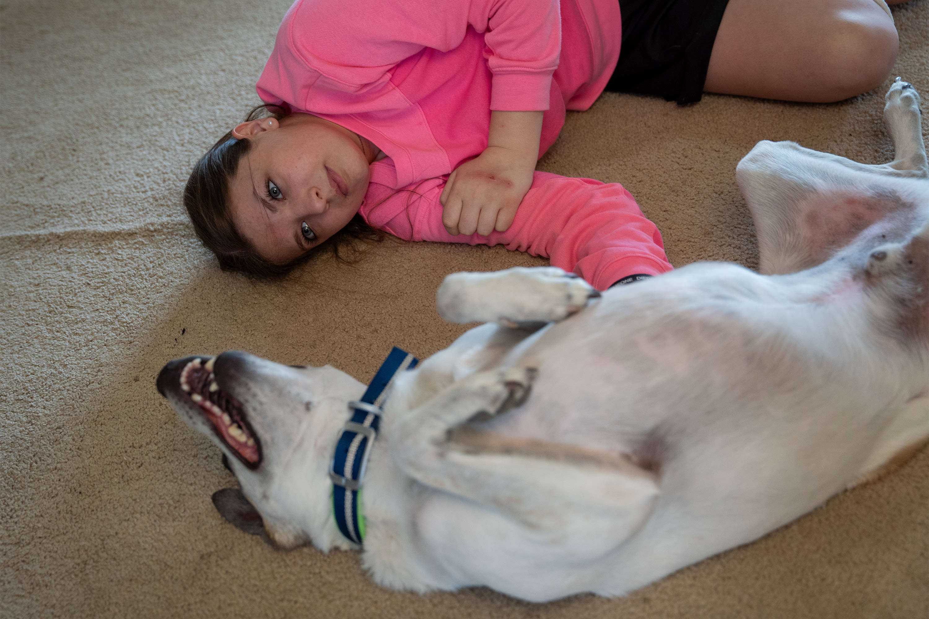 A photo of a girl lying next to her dog.