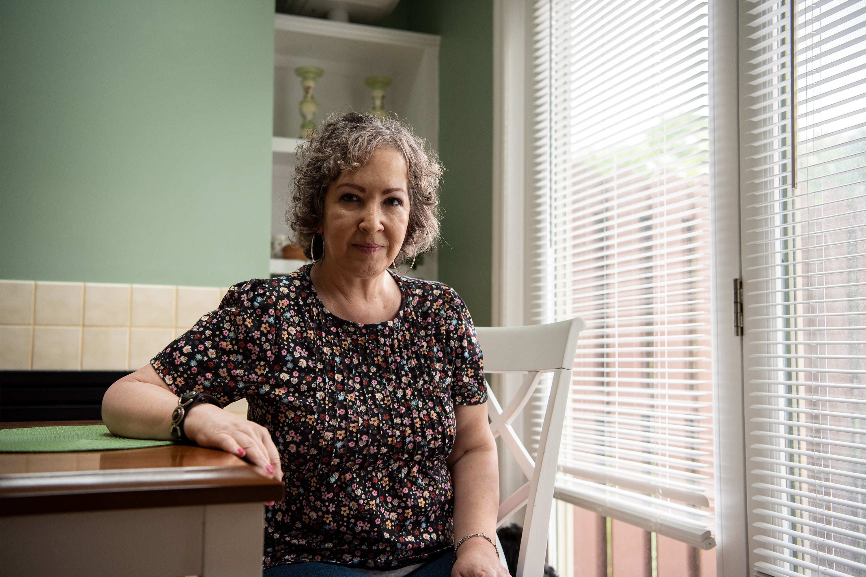 A photo of a woman sitting at her kitchen table.