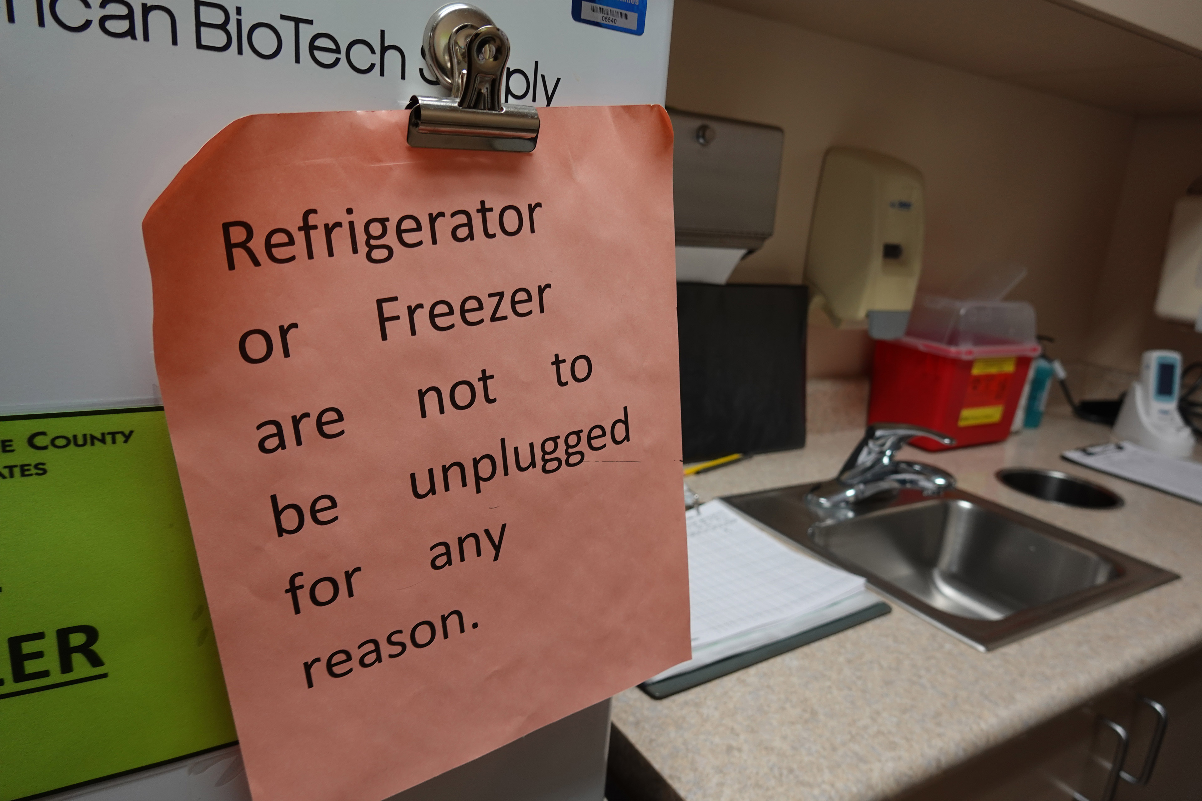 A photo of a note attached to a vaccine fridge that reads, Refrigerator or freezer are not to be unplugged for any reason.