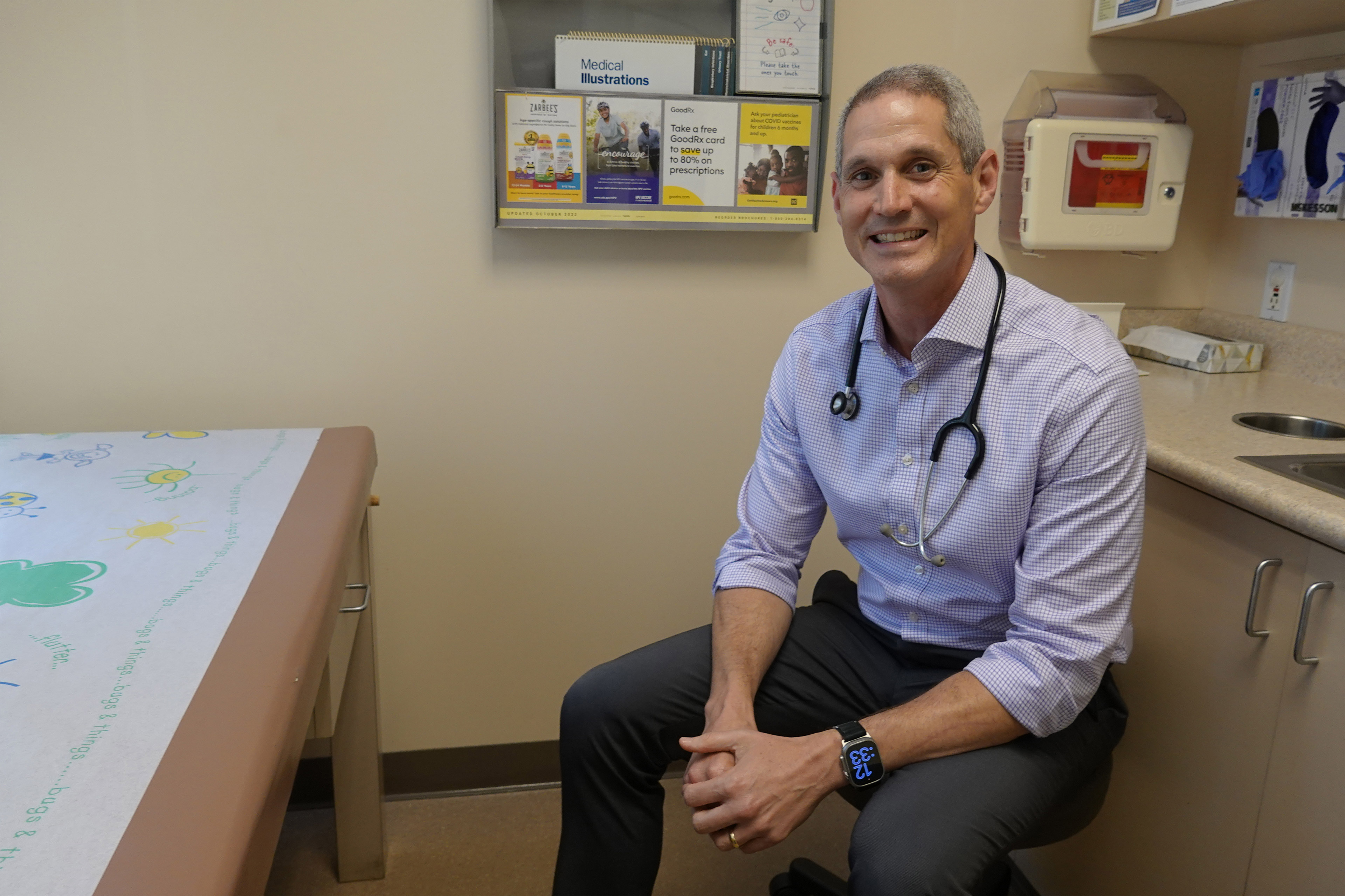 A photo of Eric Ball sitting in a chair in an exam room.