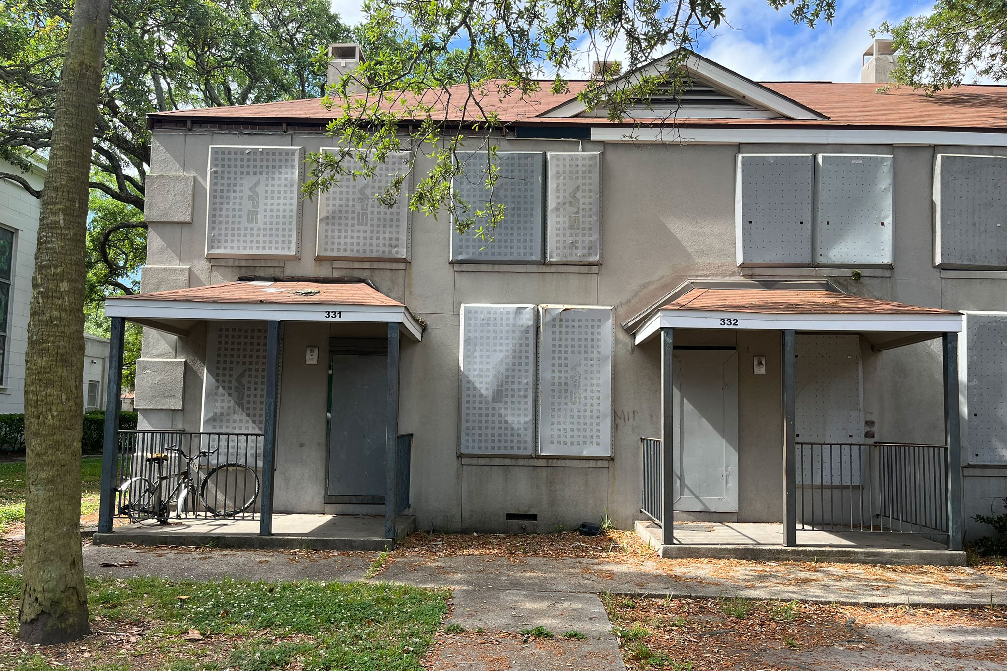 Two apartments with boarded up doors and windows are pictured.