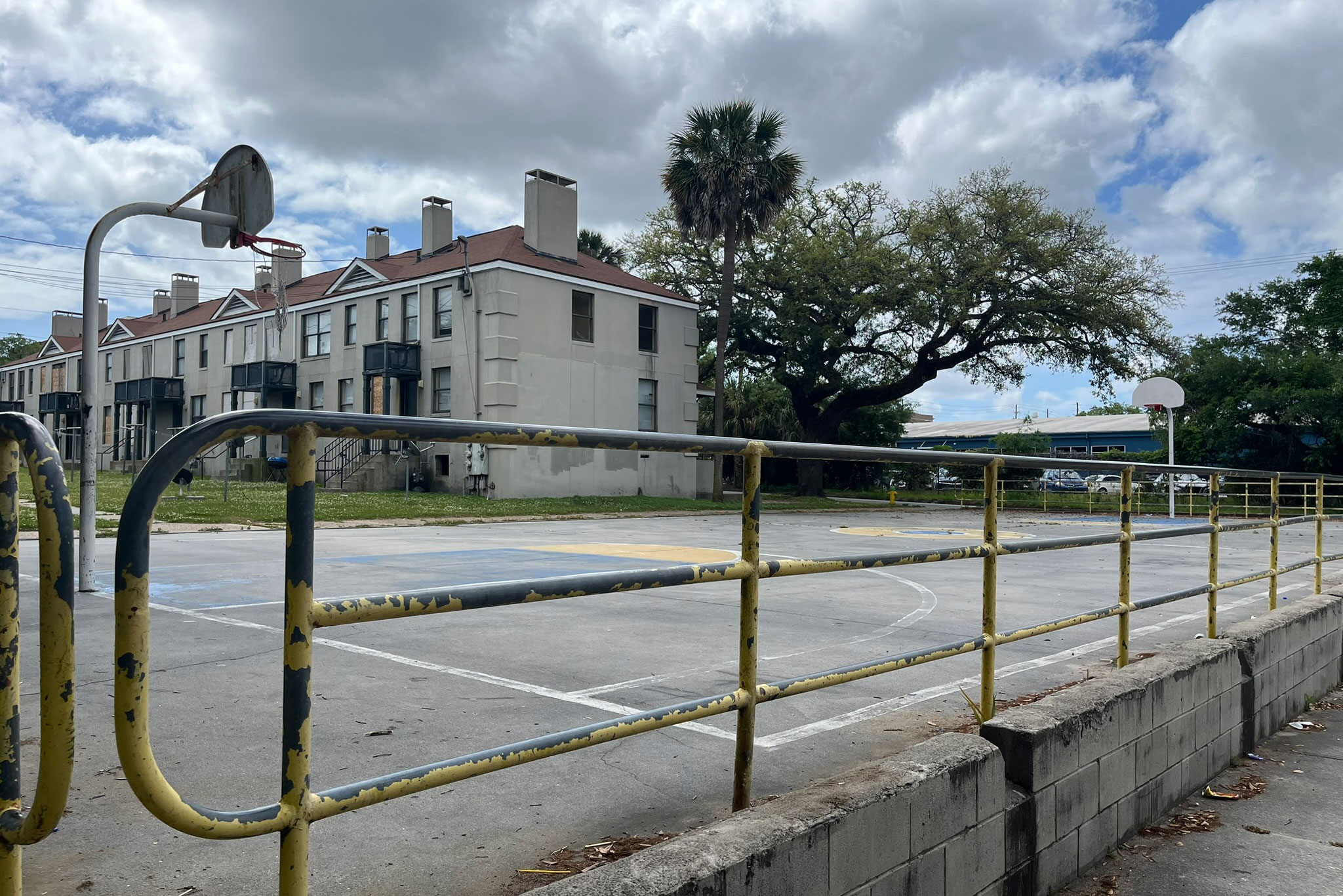 A view of Yamacraw Village from the basketball court. Yellow paint chips away from the railing along the side of the court.