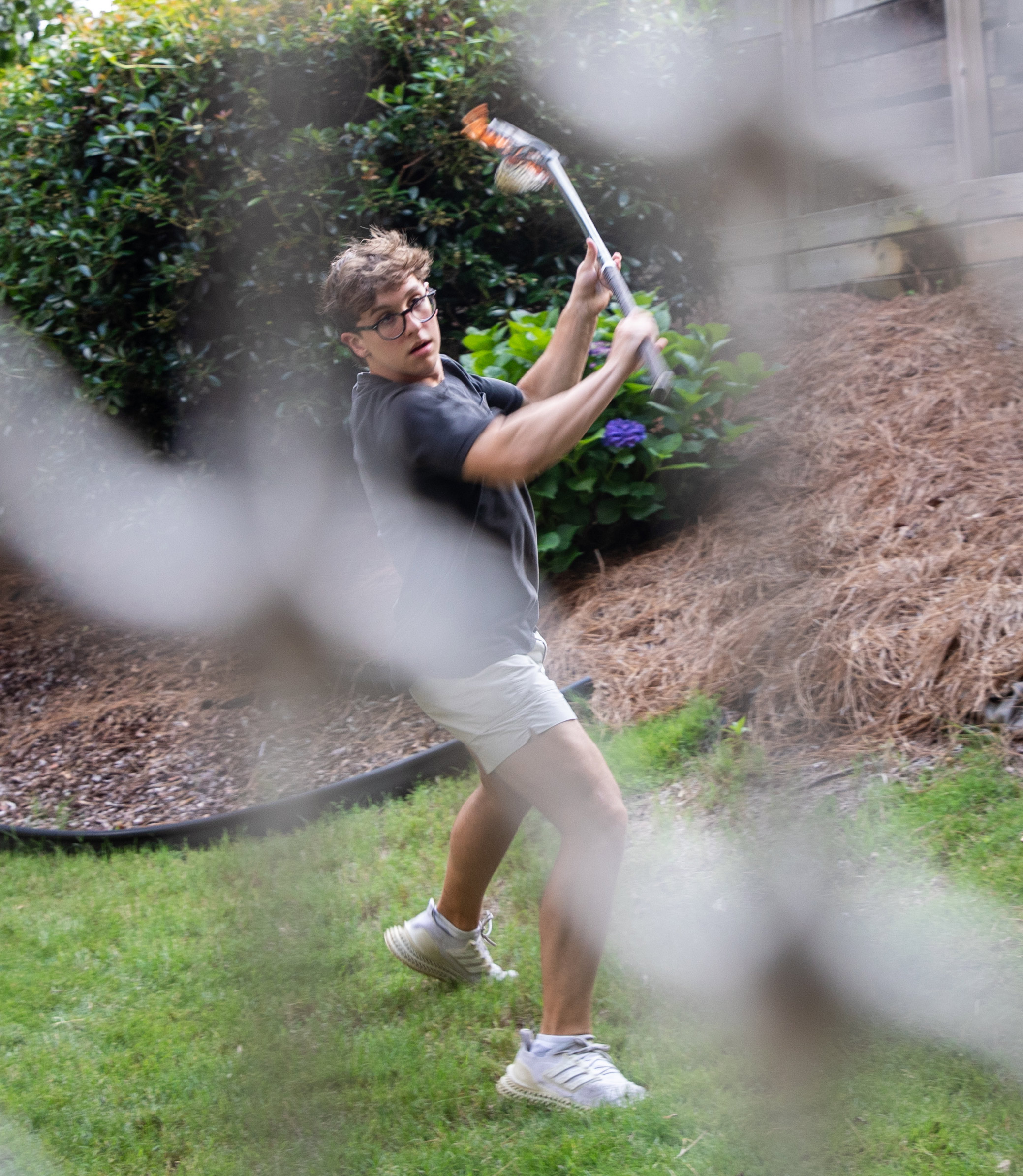 A photo of a teenager practicing. lacrosse outside.