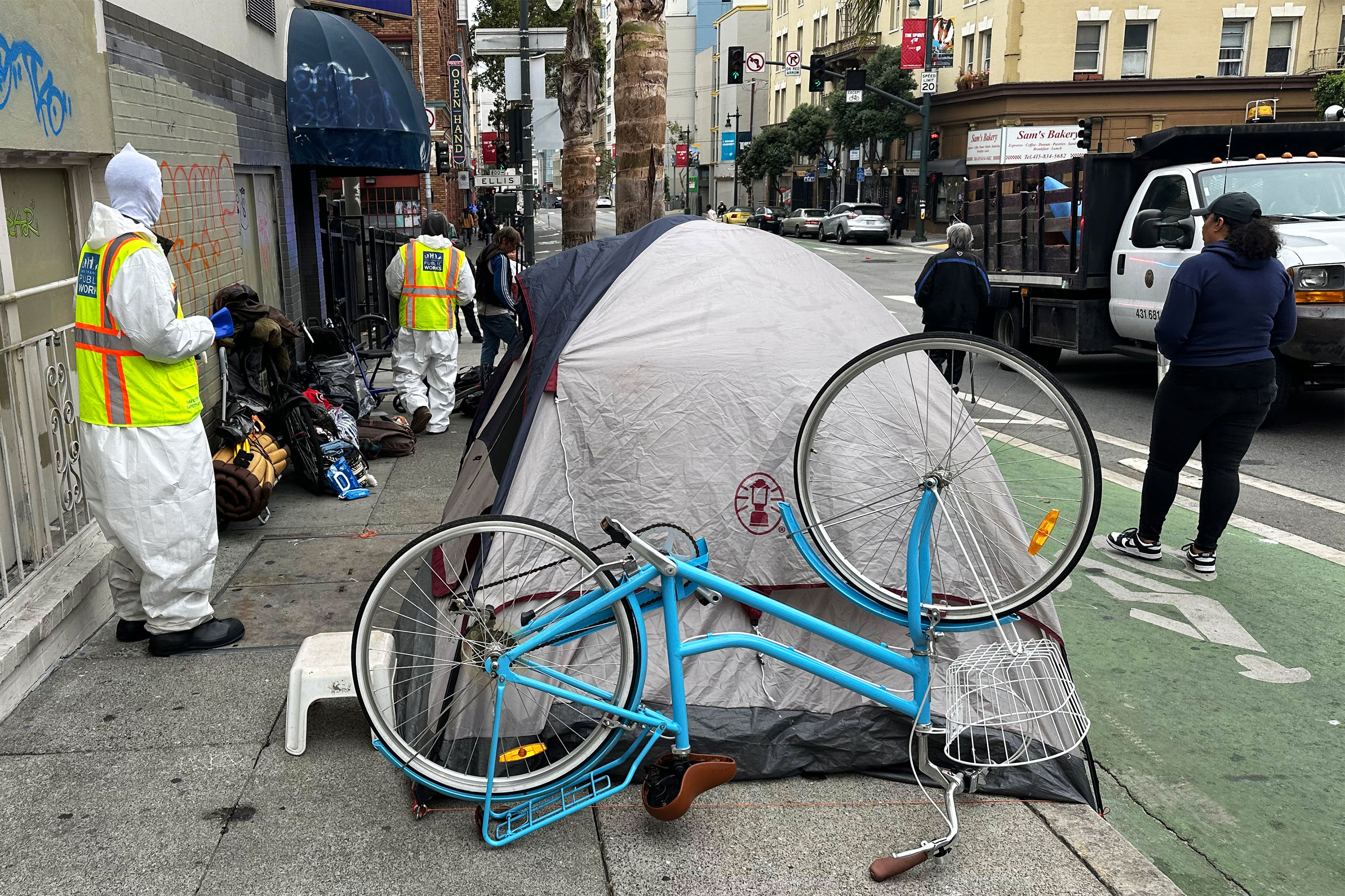 網站建置 照片中，身穿反光背心的工人站在行道上的營地旁。