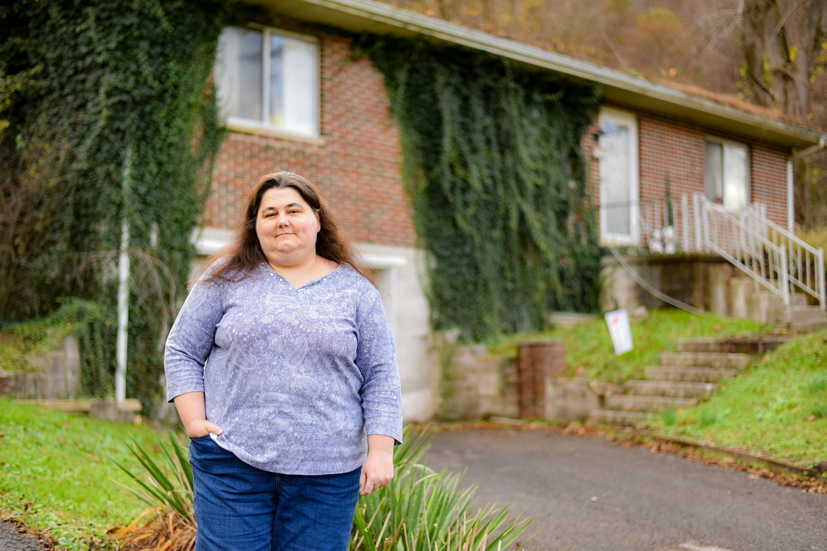 A photo of a woman standing for a photo outside of her home