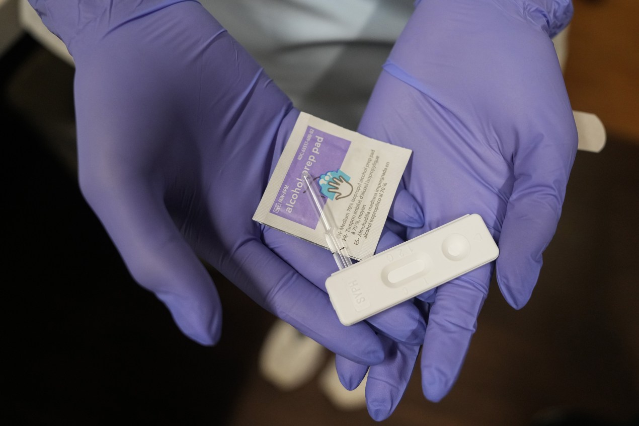 A photo of gloved hands holding a testing kit for congenital syphilis.