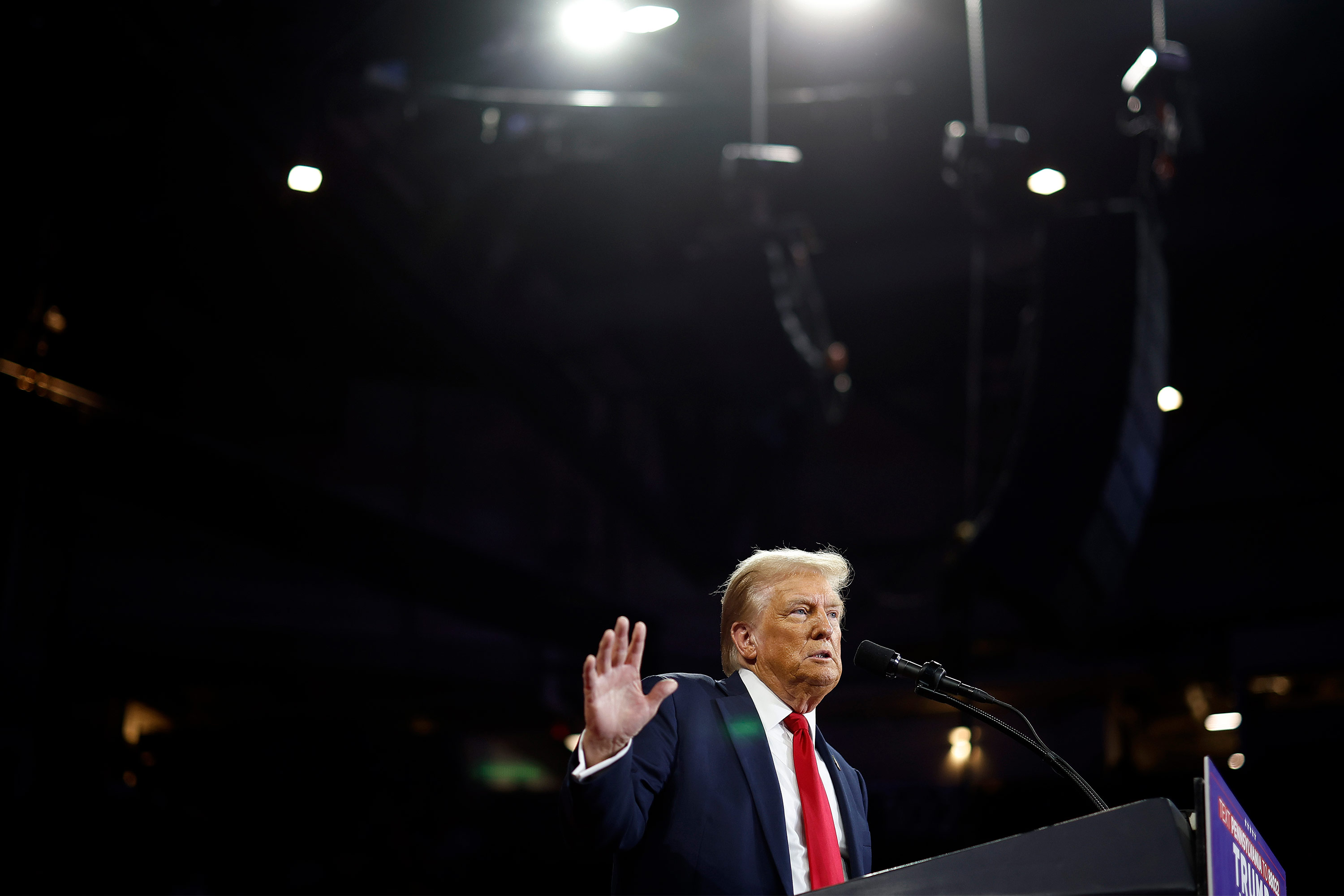 A photo of Donald Trump speaking at a podium under bright lights at a campaign event.