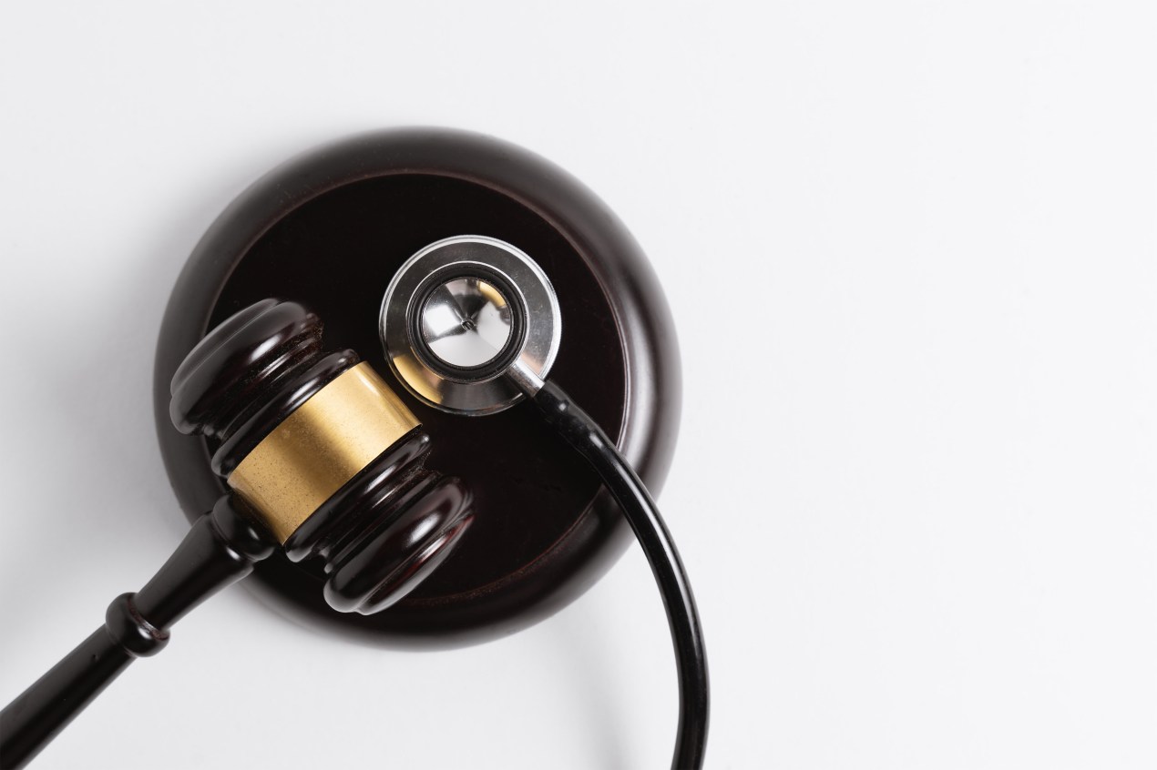 A photo of a gavel and stethoscope resting on a gavel block.