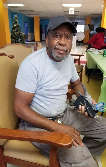 A man in a cap and tshirt is seated on a chair