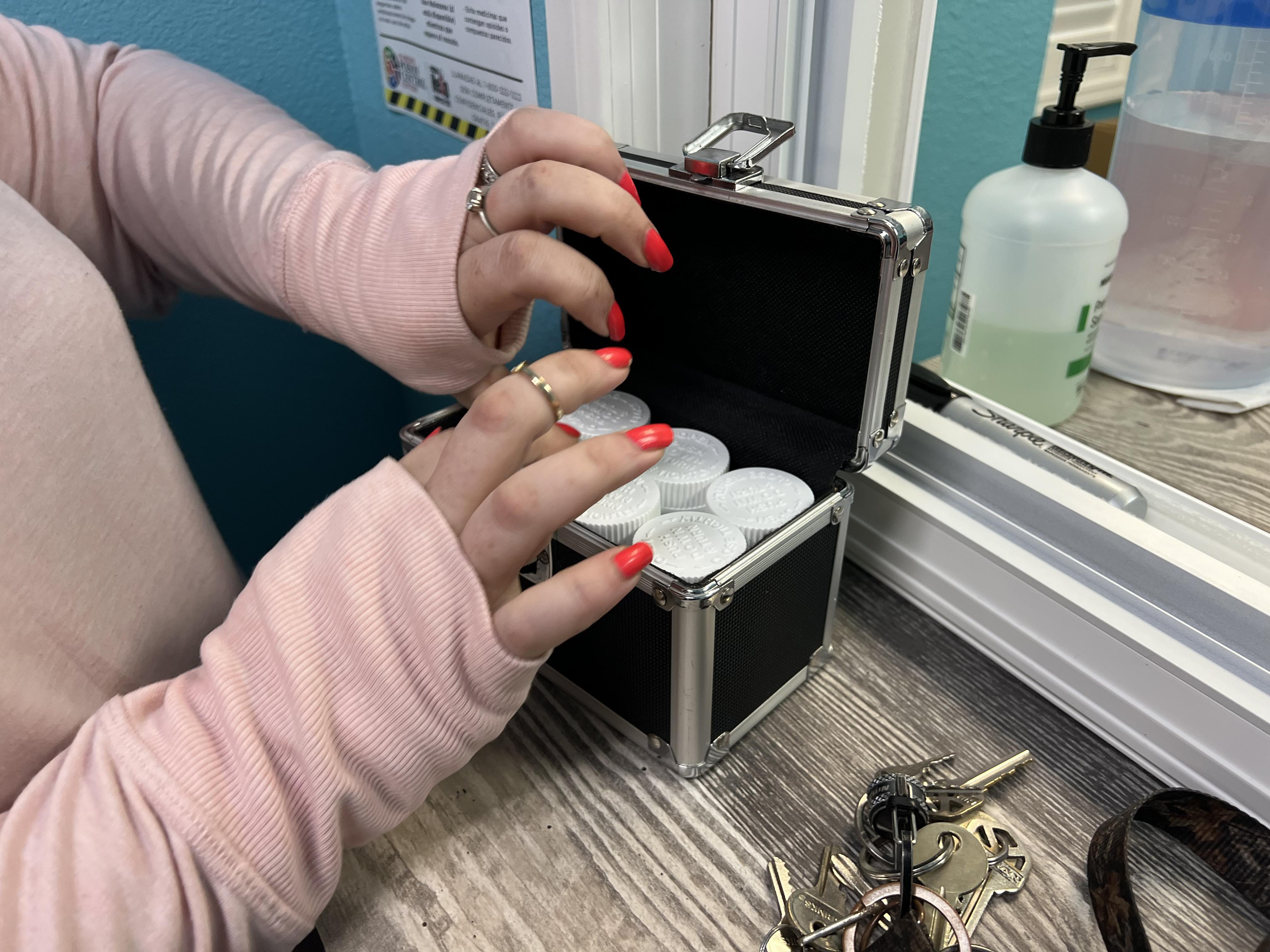 A photo of a woman placing her methadone into a lockbox.