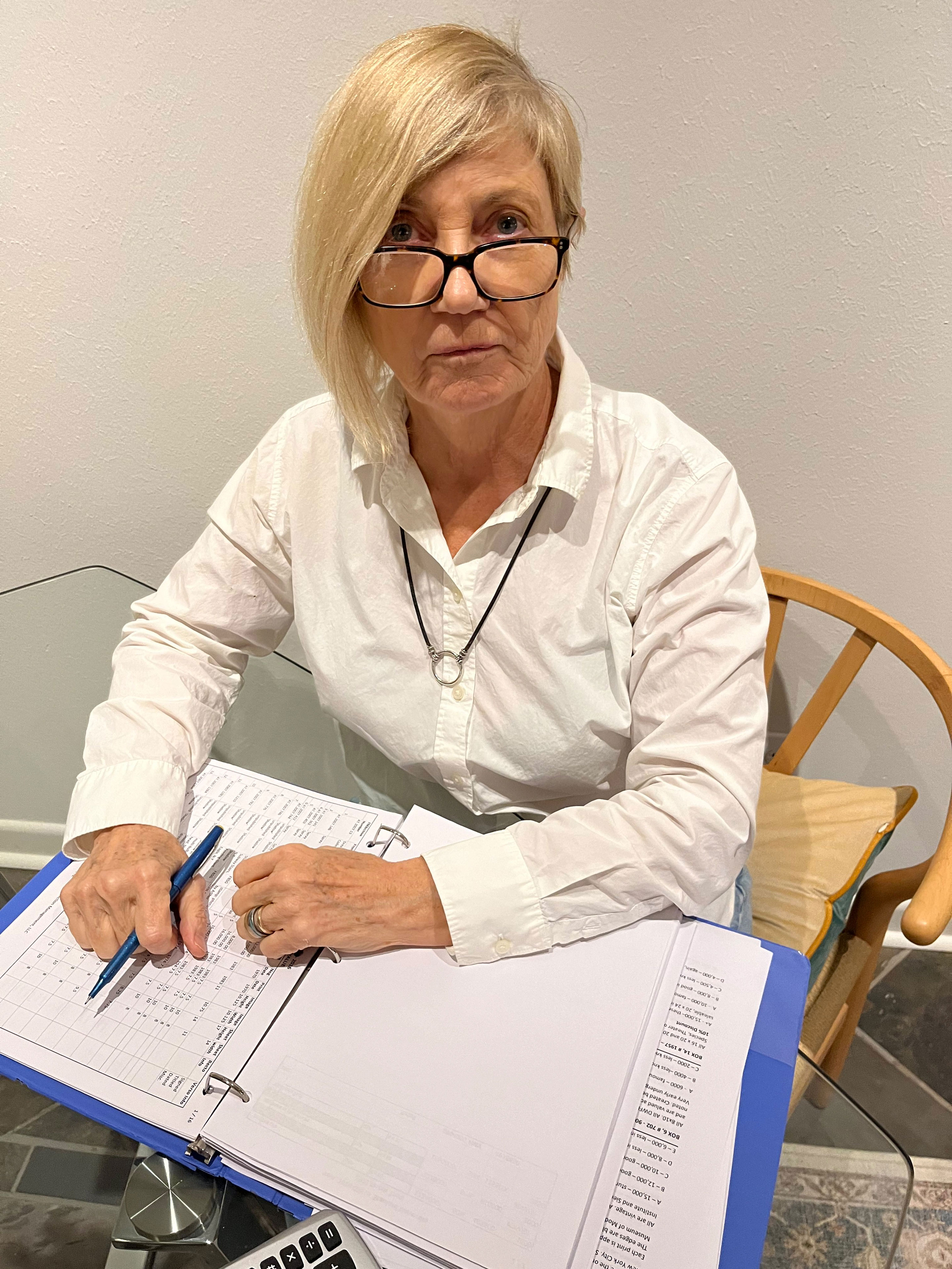 A photo of a woman sitting at a table with a binder full of papers.