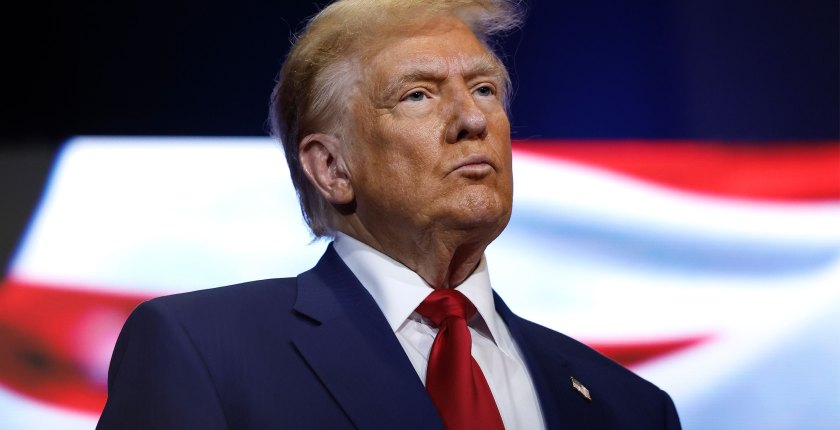 A photo of Donald Trump standing in front of a screen.