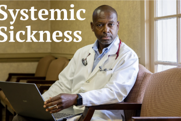 A portrait of a doctor sitting in a chair and looking towards the viewer.