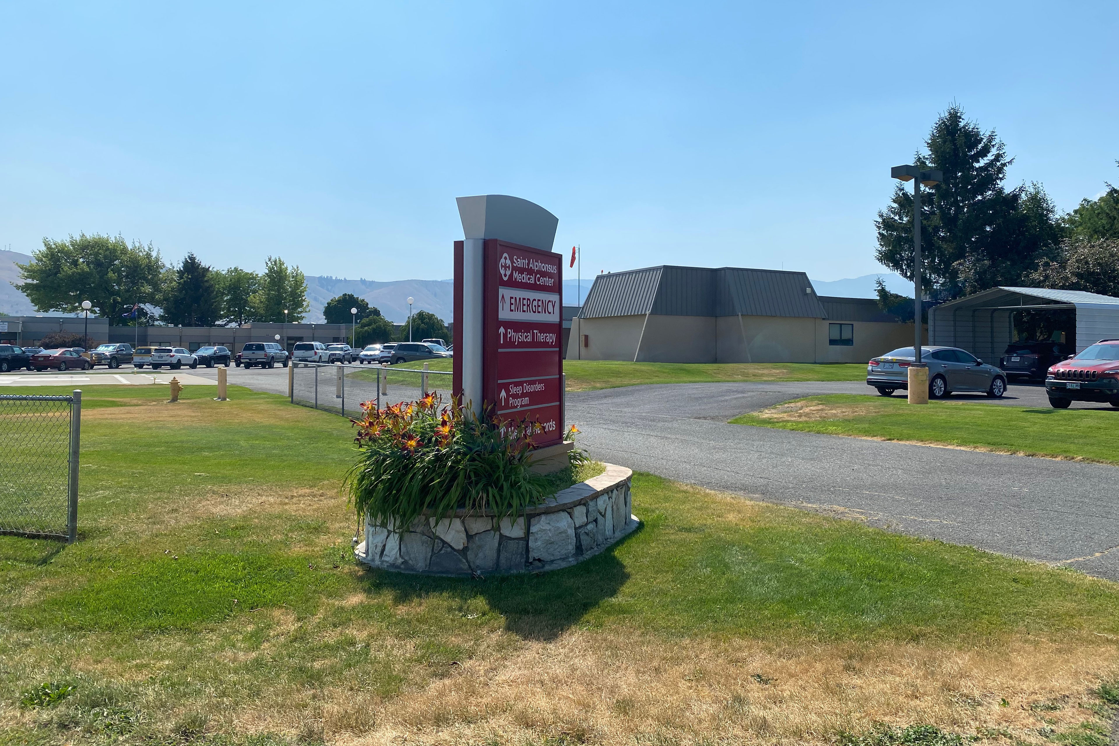 A photograph of the exterior of a medical building on a sunny day. A sign