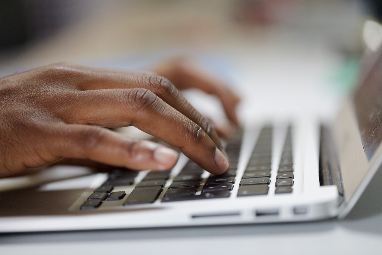 A photo of hands typing on a laptop keyboard.