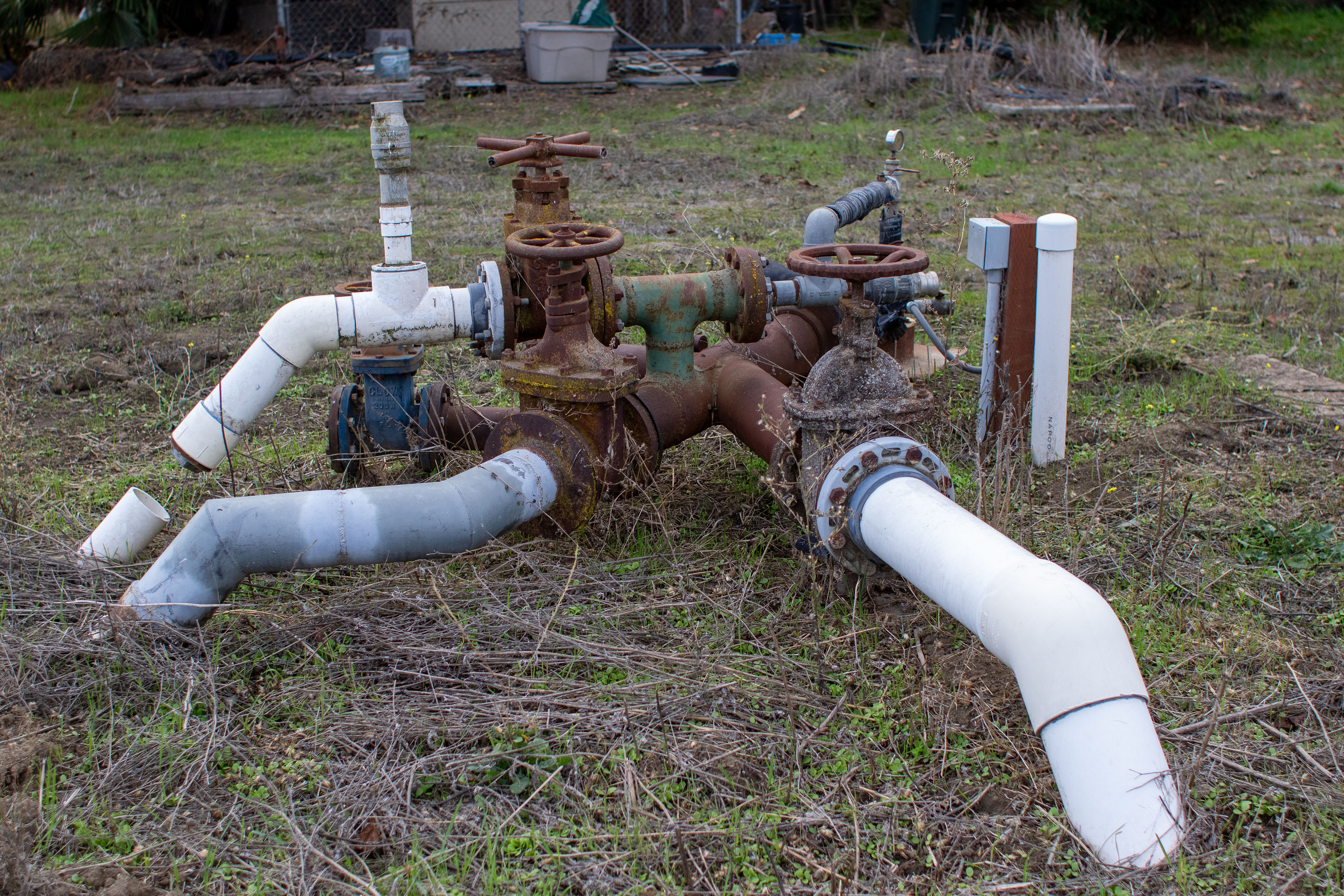 Above-ground water pipes. Some are rusted and others are made of white plastic.