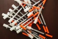 A pile of medical syringes on wooden background.