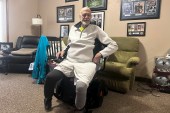 A photo of a man inside an apartment, seated in a wheelchair.