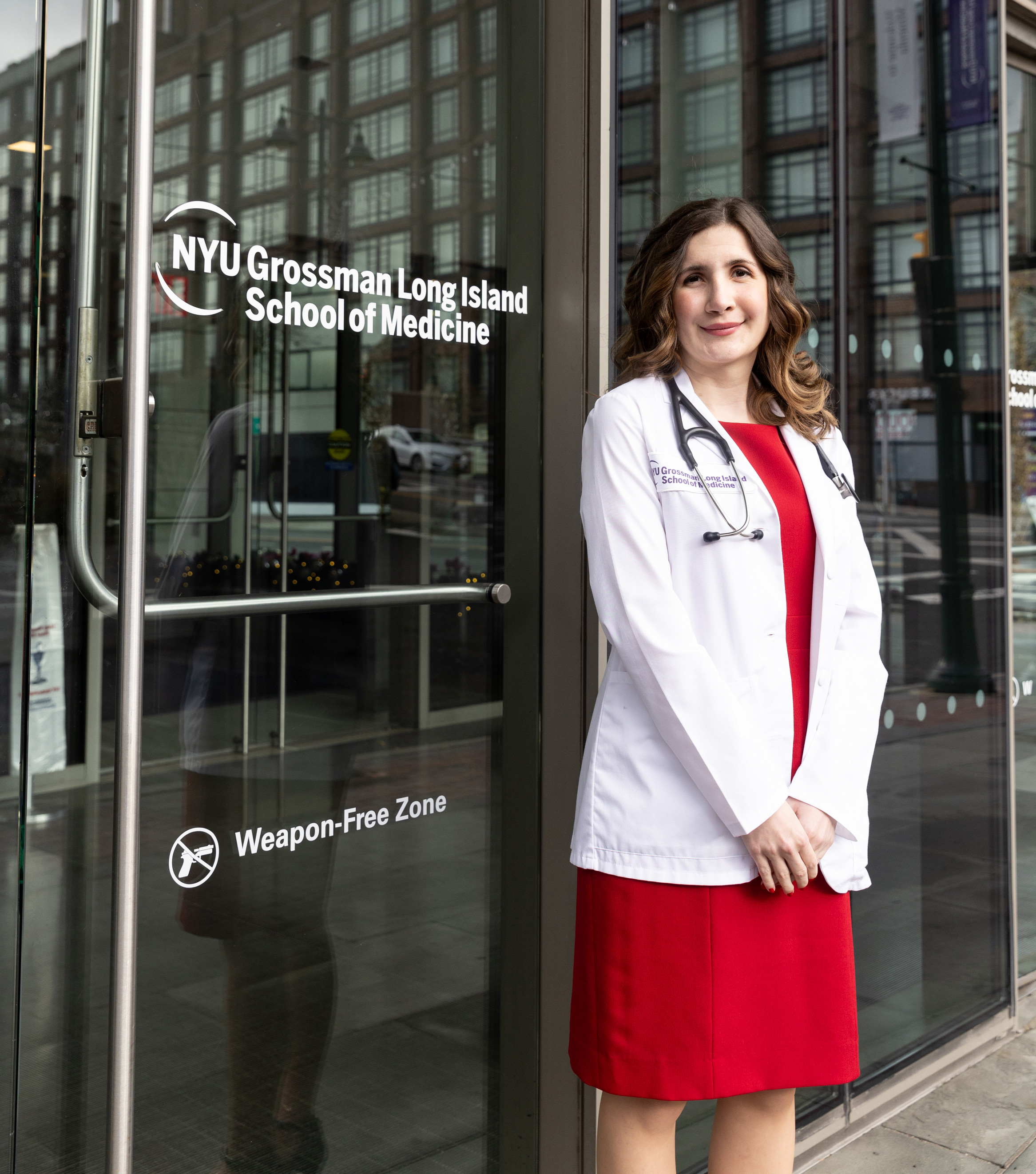 A photo of Julia Lo Cascio standing outside a door with NYU Grossman Long Island School of Medicine's logo on it.