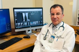 A photo of a doctor sitting at his desk with an x-ray image pulled up on his computer.