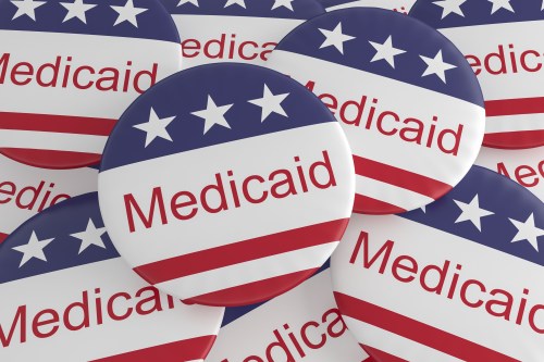 A pile of pins that say "Medicaid" and are decorated with an American flag pattern.