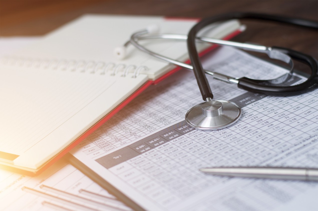 A photo of a stethoscope resting on top of medical documents and a notebook.