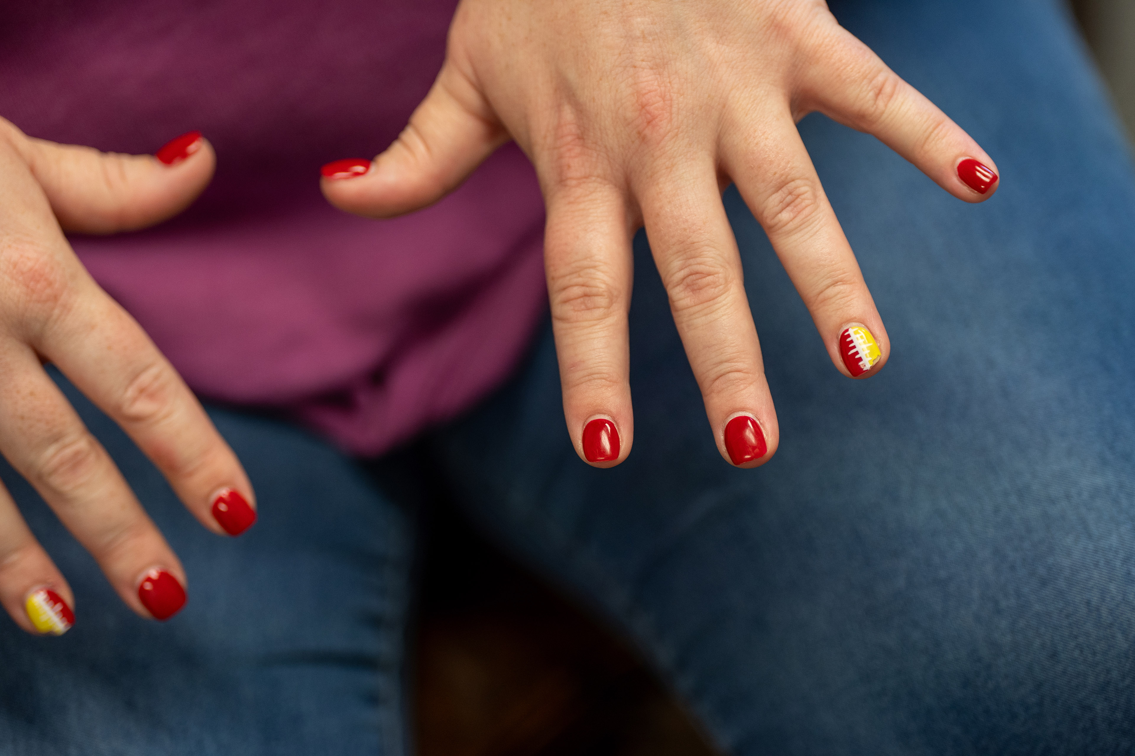 A woman shows her manicured fingernails, painted in a Kansas City Chiefs theme