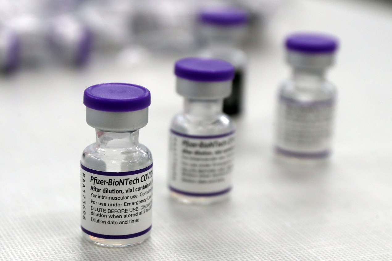 A photo of several vials of Pfizer's covid-19 vaccine arranged on a table.