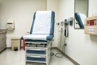 A doctor office examination room with the examination table/reclining chair in its most upright position.