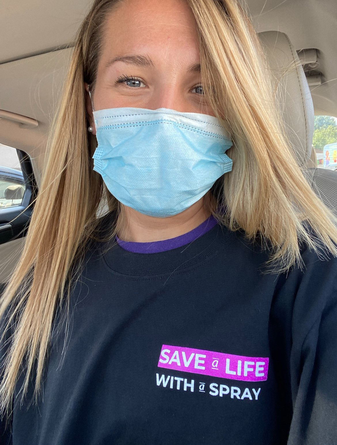 A photo of a white woman wearing a mask and a shirt that reads, "Save a life with a spray."